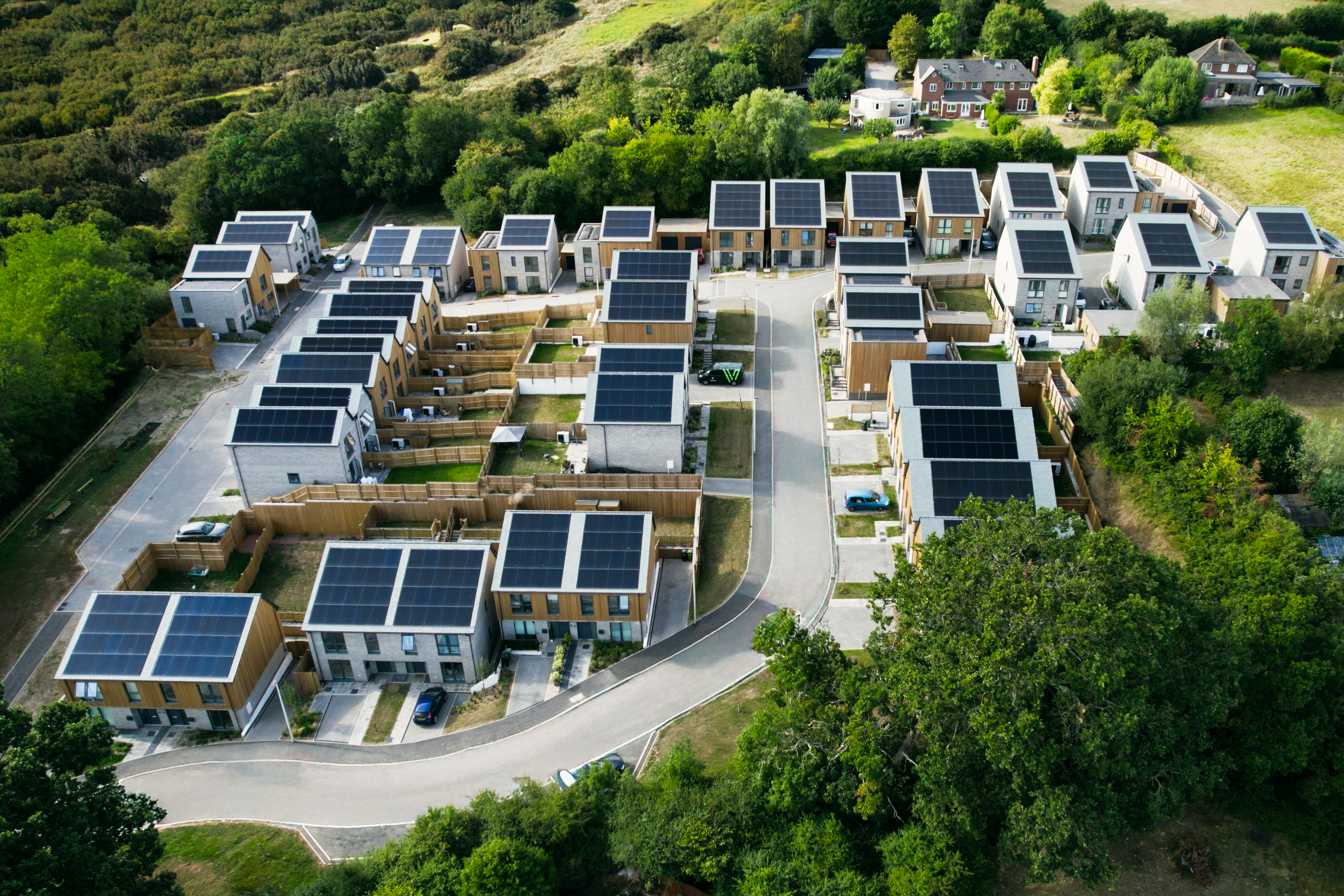Aerial view of a solar-powered zero-carbon housing development surrounded by trees